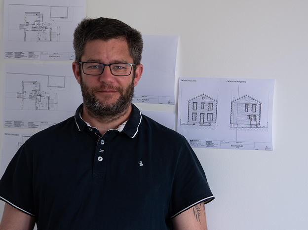 Homme barbu avec des lunettes devant des plans architecturaux d'une maison à Cormeilles-en-Parisis dans le Val d'Oise 95